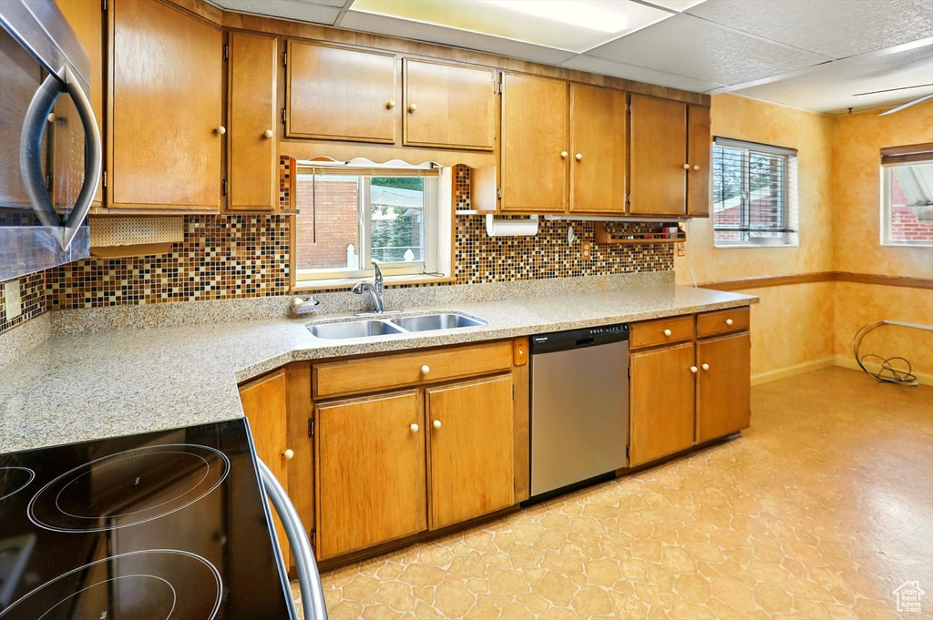 Kitchen featuring stainless steel appliances, light countertops, tasteful backsplash, and brown cabinetry