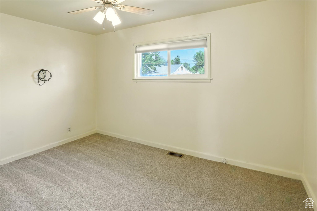 Unfurnished room featuring light carpet and a ceiling fan