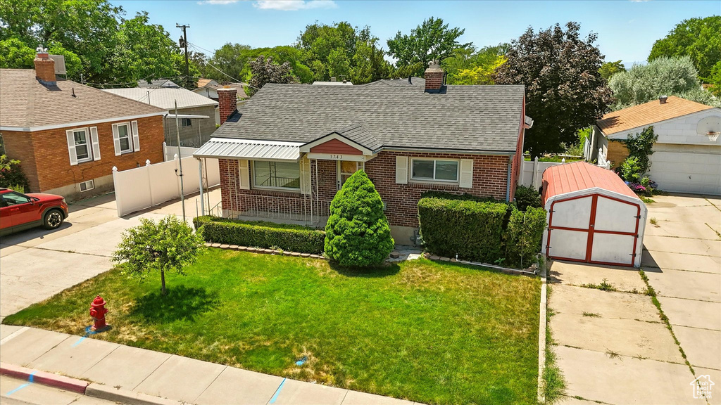 View of front facade featuring brick siding, a chimney, a shingled roof, a gate, and concrete driveway