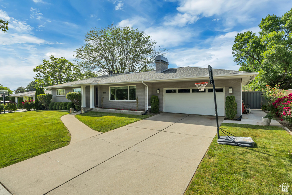 Single story home featuring brick siding, an attached garage, a chimney, driveway, and roof with shingles