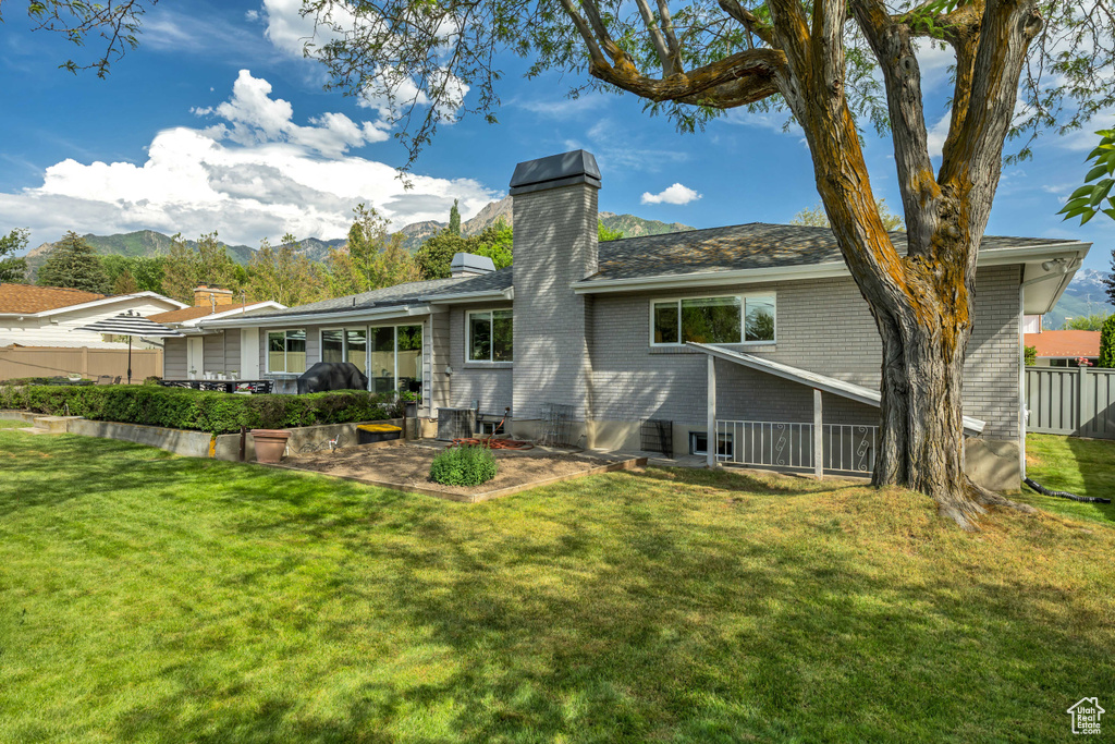Rear view of property featuring a patio, a chimney, brick siding, and a mountain view