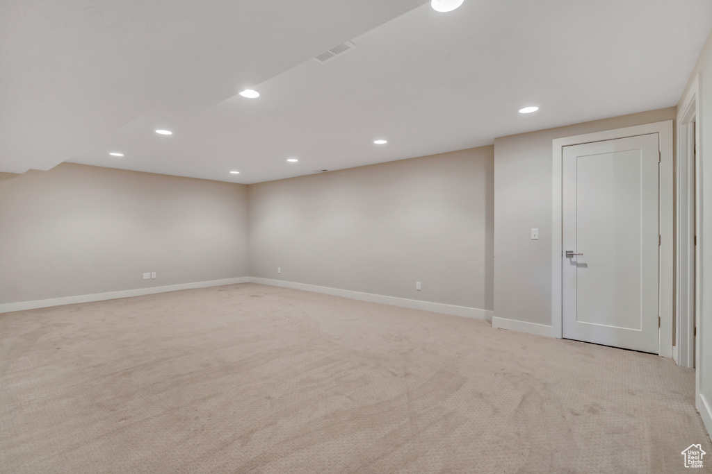 Finished basement with light colored carpet and recessed lighting