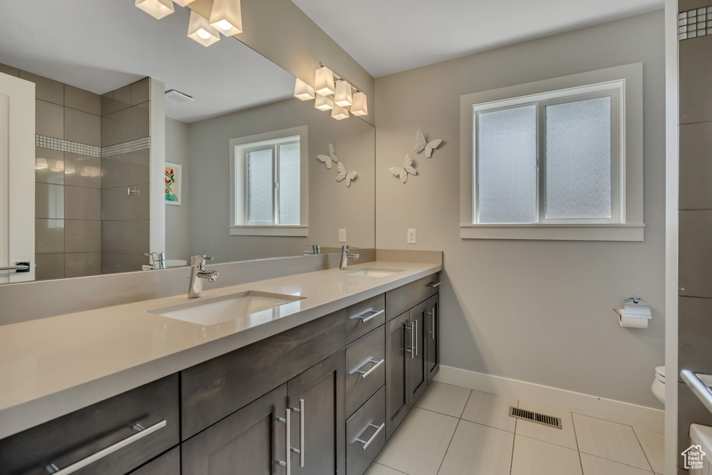Bathroom featuring double vanity, tile patterned flooring, and a tile shower