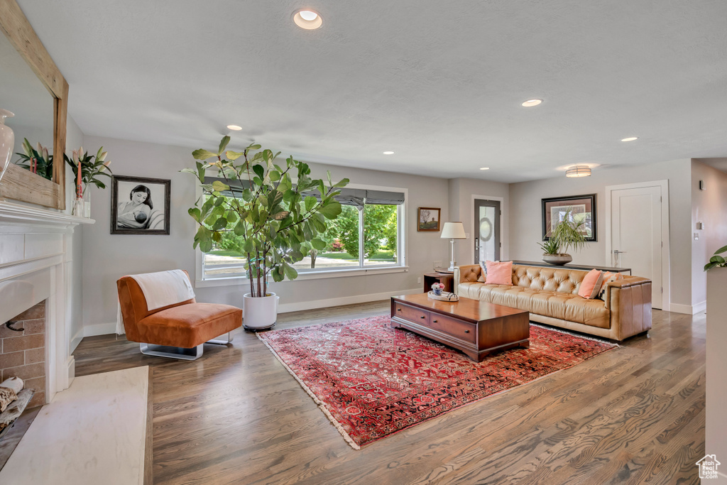 Living room featuring a fireplace with flush hearth, wood finished floors, and recessed lighting
