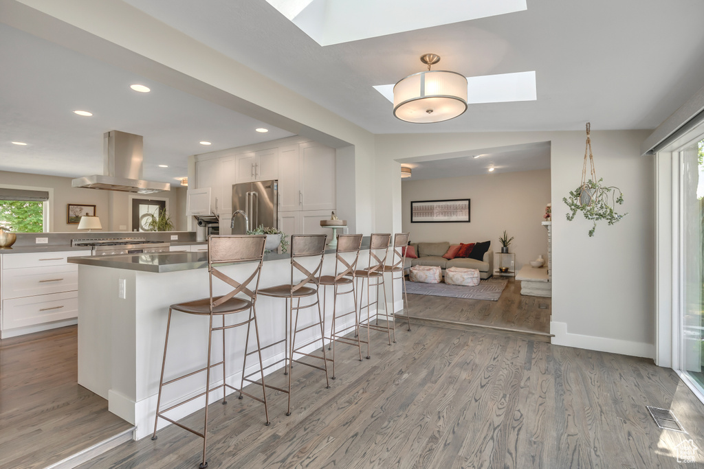 Kitchen with island range hood, high end refrigerator, a peninsula, a breakfast bar, and a skylight