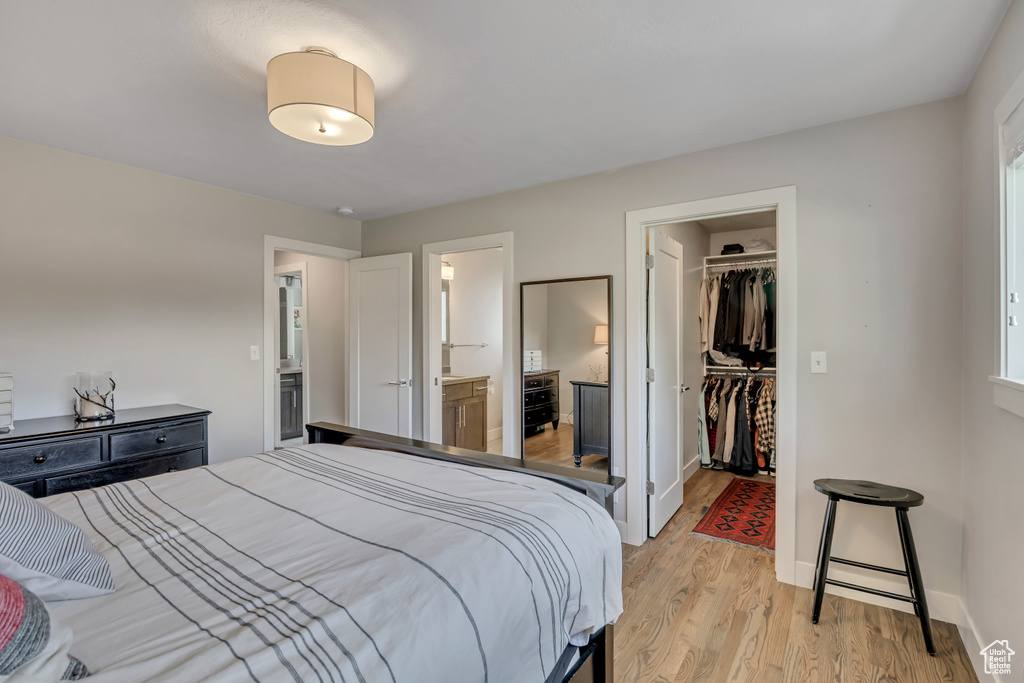 Bedroom featuring a spacious closet, light wood-style floors, a closet, and ensuite bathroom