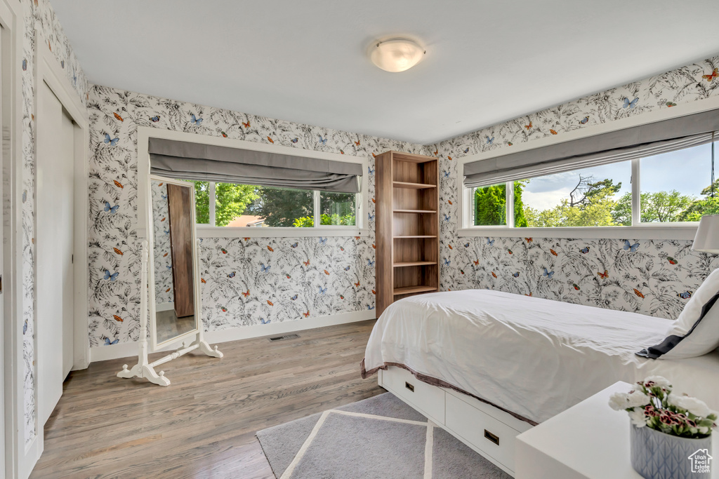 Bedroom with wallpapered walls and wood finished floors