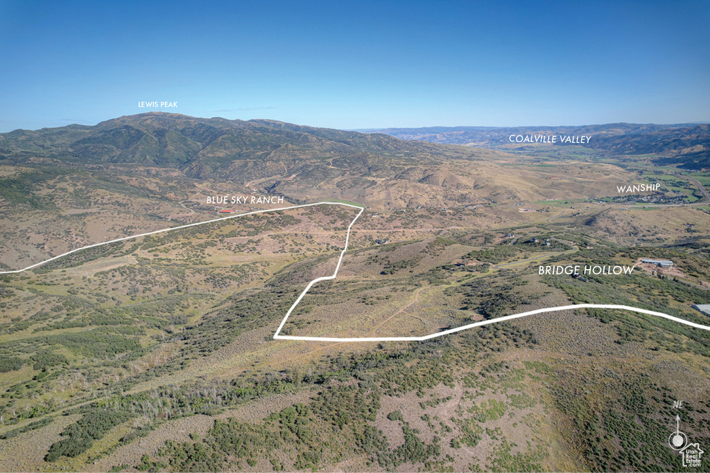Aerial view of property and surrounding area with property parcel outlined and a mountain backdrop