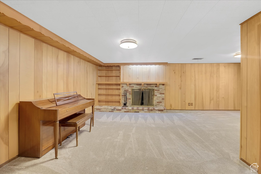 Living room featuring light carpet, wooden walls, and a brick fireplace