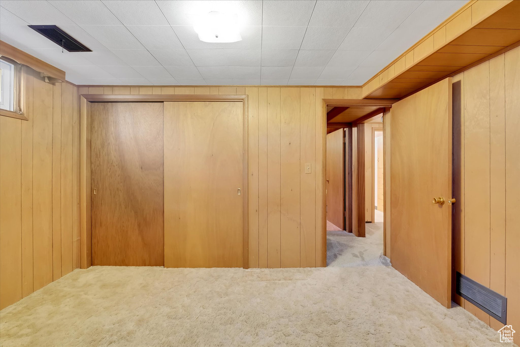 Unfurnished bedroom with carpet, a closet, and wood walls