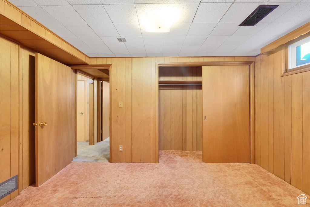 Unfurnished bedroom featuring carpet flooring, a closet, and wood walls
