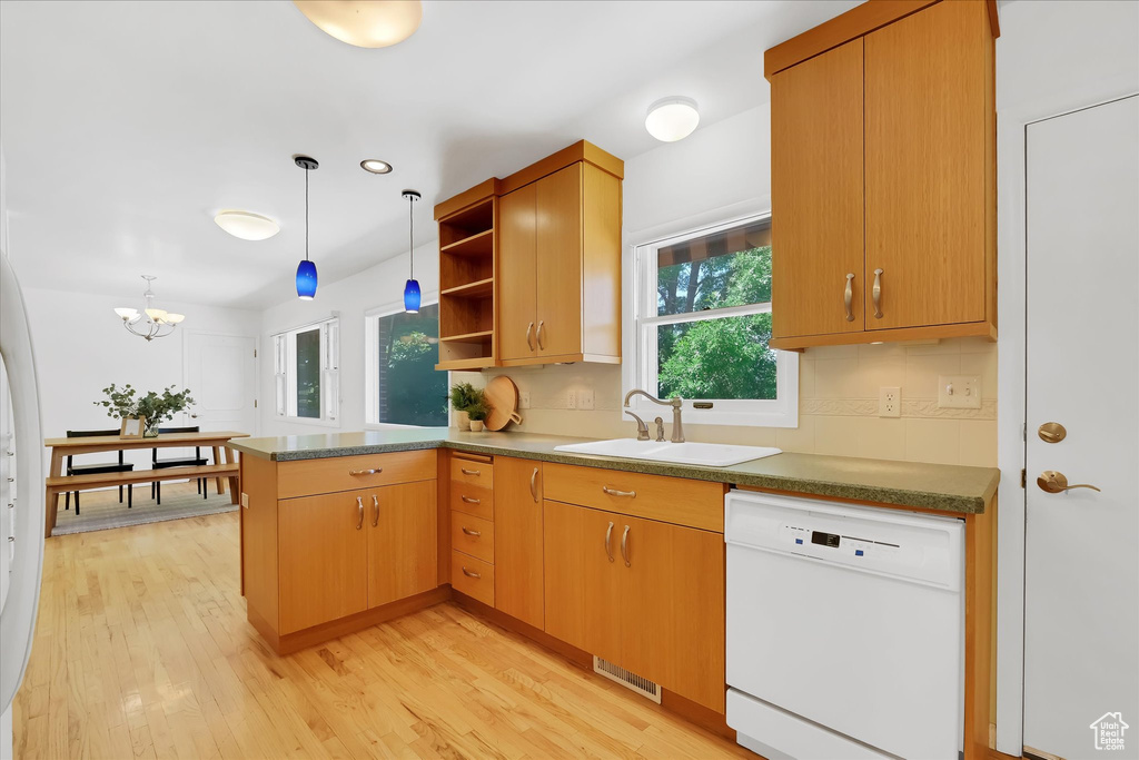 Kitchen with white dishwasher, a peninsula, open shelves, light wood finished floors, and hanging light fixtures