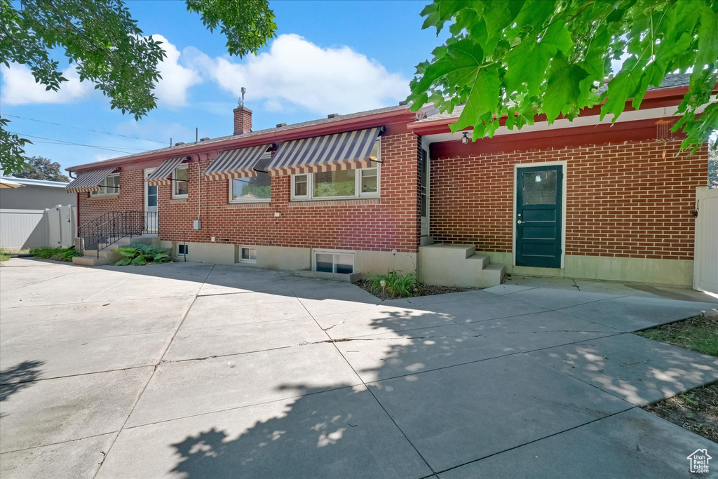 Back of property with a chimney, brick siding, and a patio area