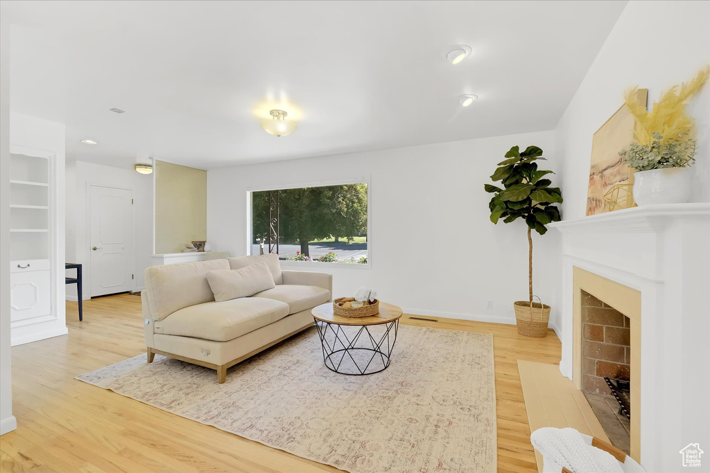 Living room with light wood-type flooring and a fireplace with flush hearth