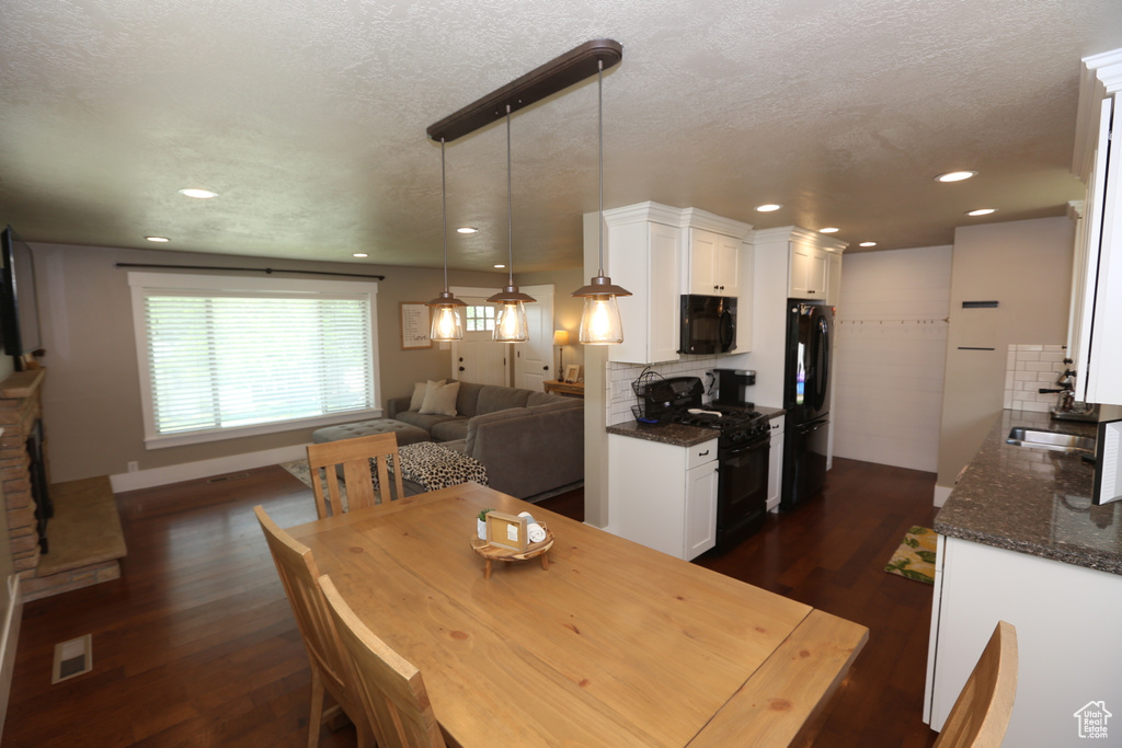 Dining space with dark wood finished floors, a textured ceiling, and recessed lighting