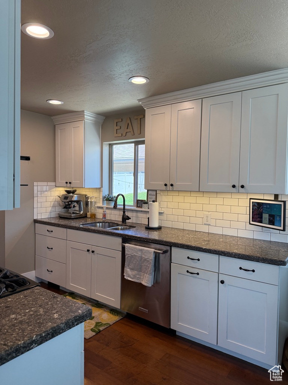 Kitchen featuring stainless steel dishwasher, dark wood-style flooring, dark stone counters, a textured ceiling, and decorative backsplash