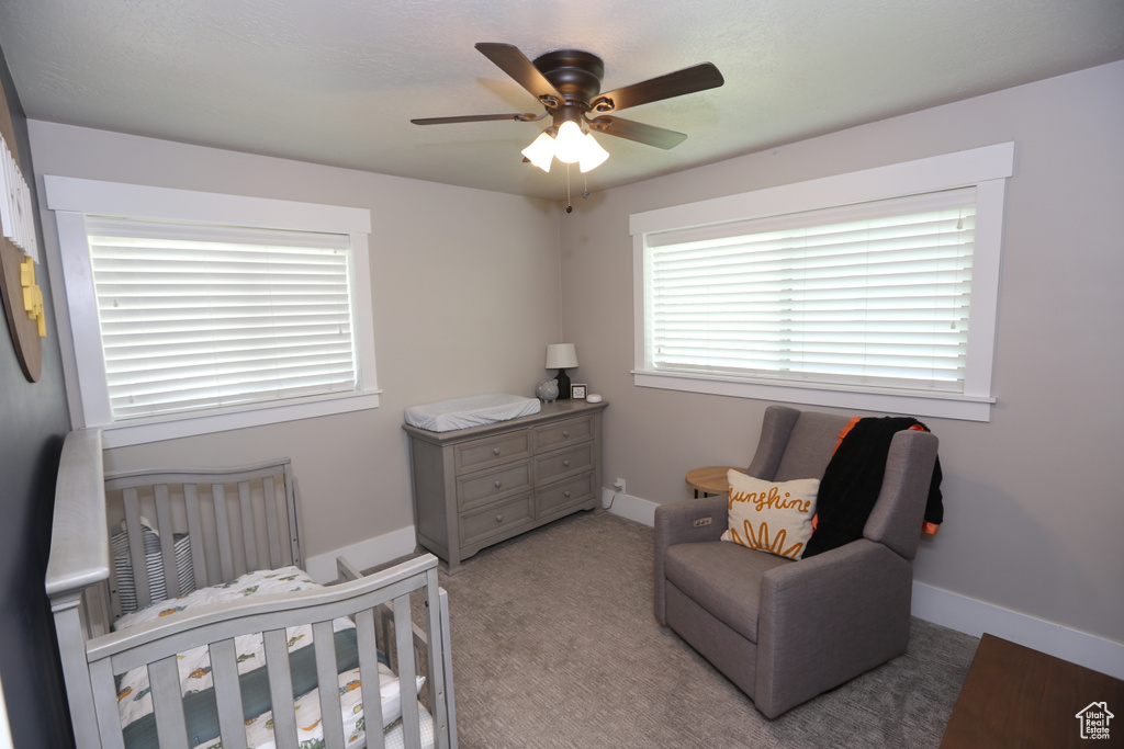 Carpeted bedroom with a nursery area and a ceiling fan
