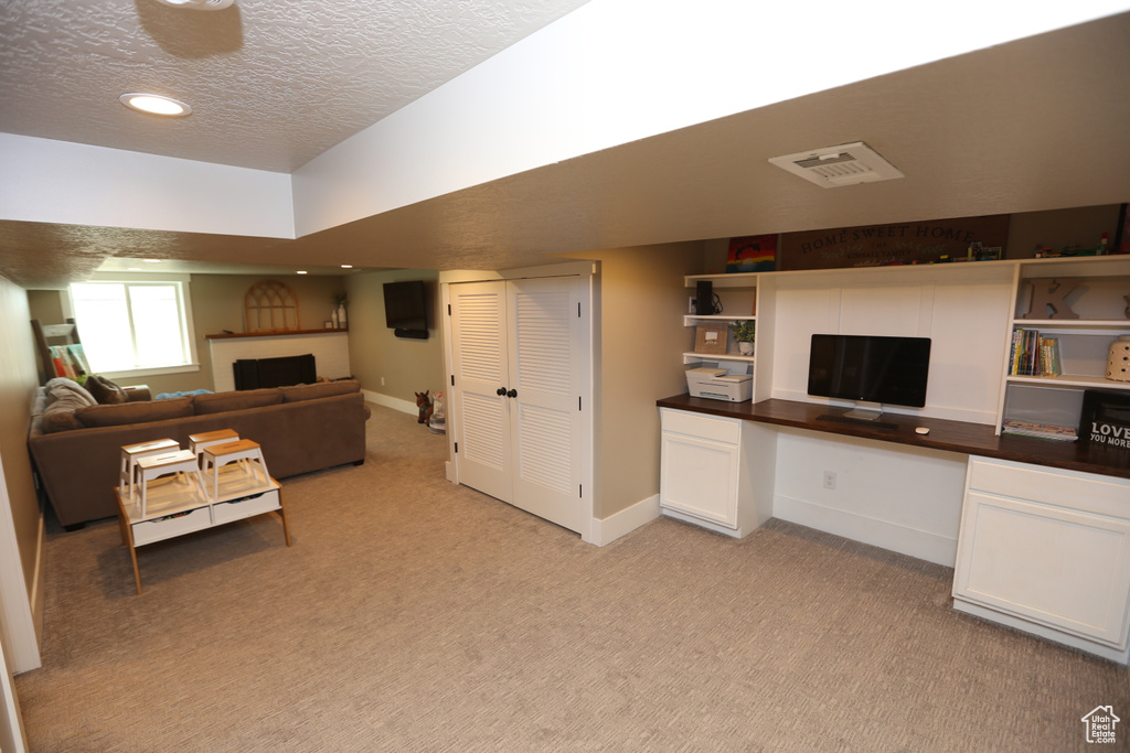 Living room featuring light carpet, built in study area, a textured ceiling, recessed lighting, and a fireplace