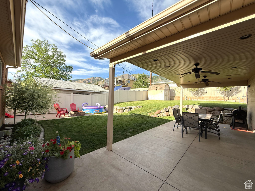 Fenced backyard with a storage unit, outdoor dining space, a patio, and an outdoor fire pit