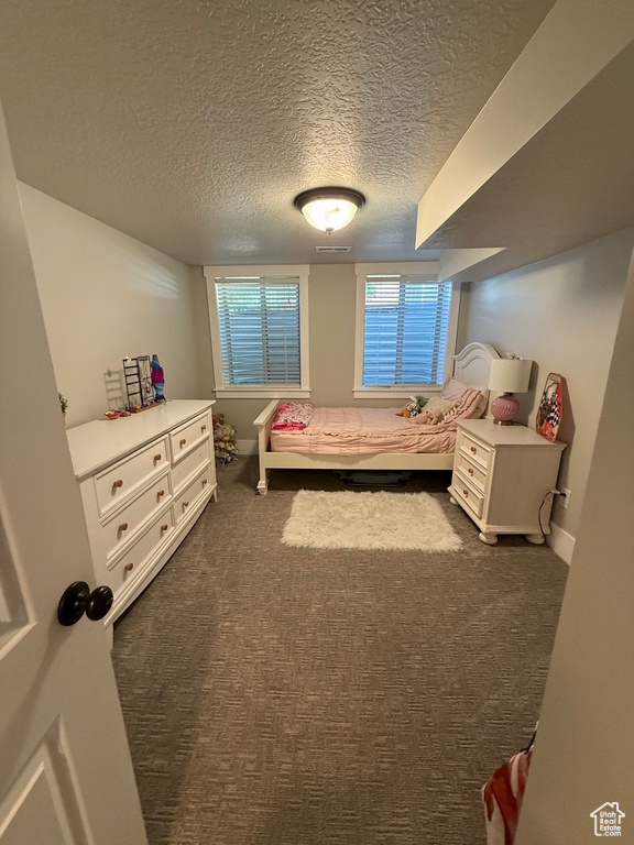 Bedroom featuring dark carpet and a textured ceiling