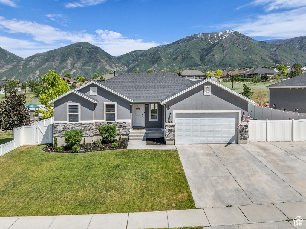 View of front of property featuring stucco siding, stone siding, an attached garage, driveway, and a mountain view