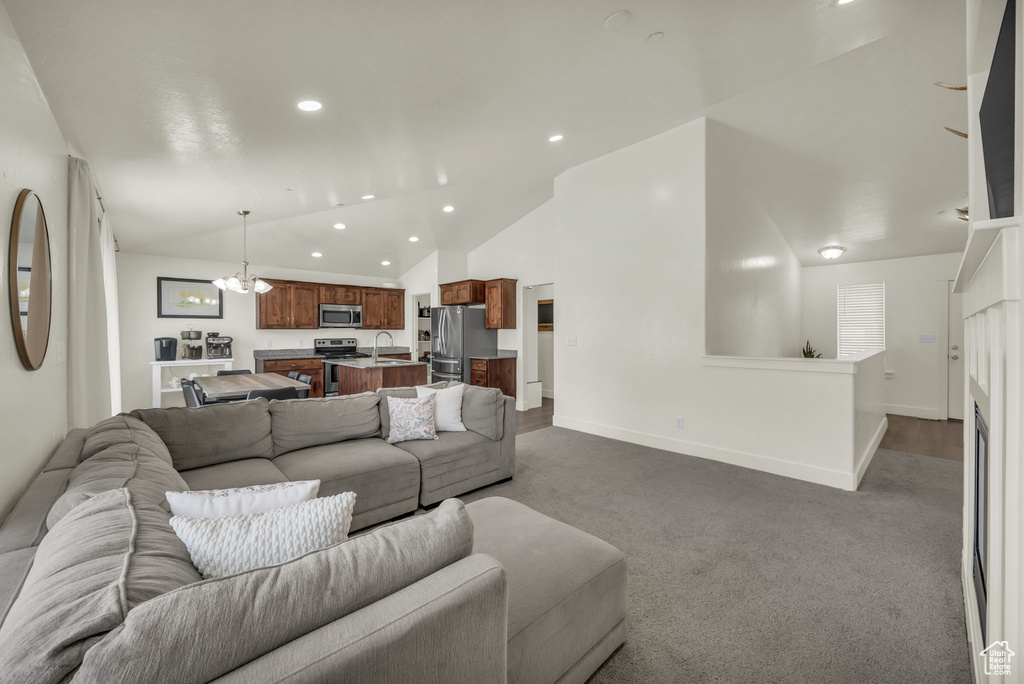 Living room with recessed lighting, dark carpet, vaulted ceiling, and a chandelier