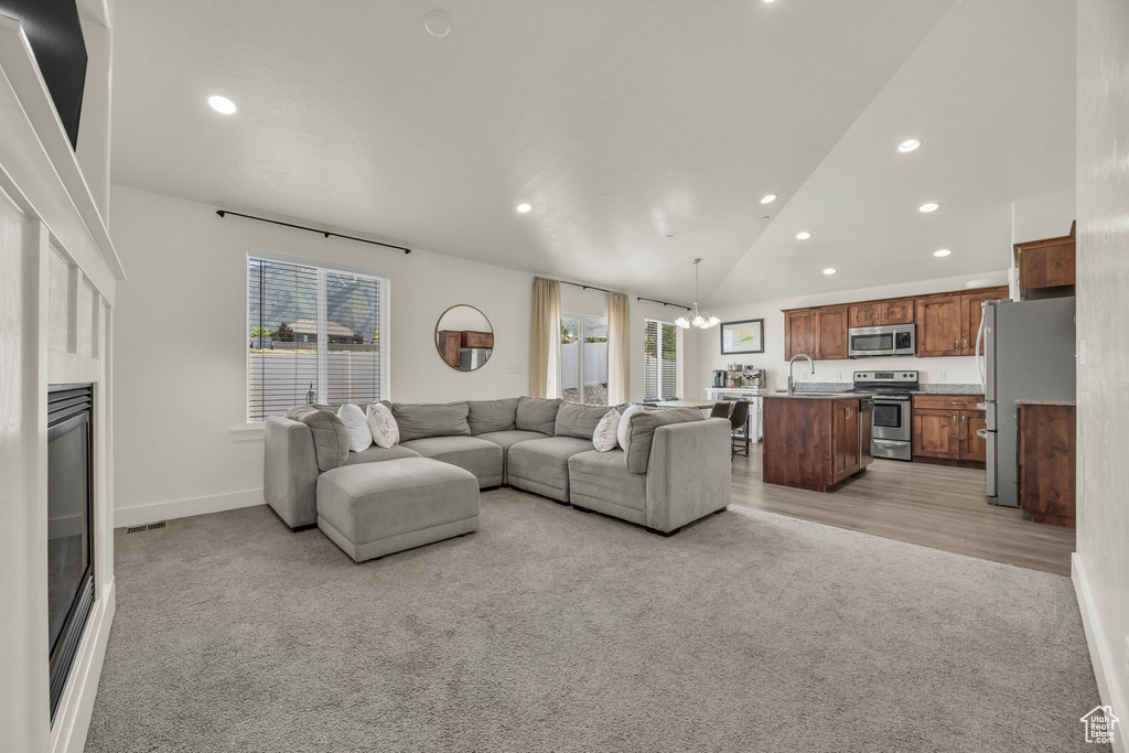 Living area featuring light carpet, a chandelier, healthy amount of natural light, recessed lighting, and vaulted ceiling
