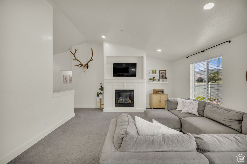 Living area with carpet flooring, recessed lighting, lofted ceiling, and a glass covered fireplace