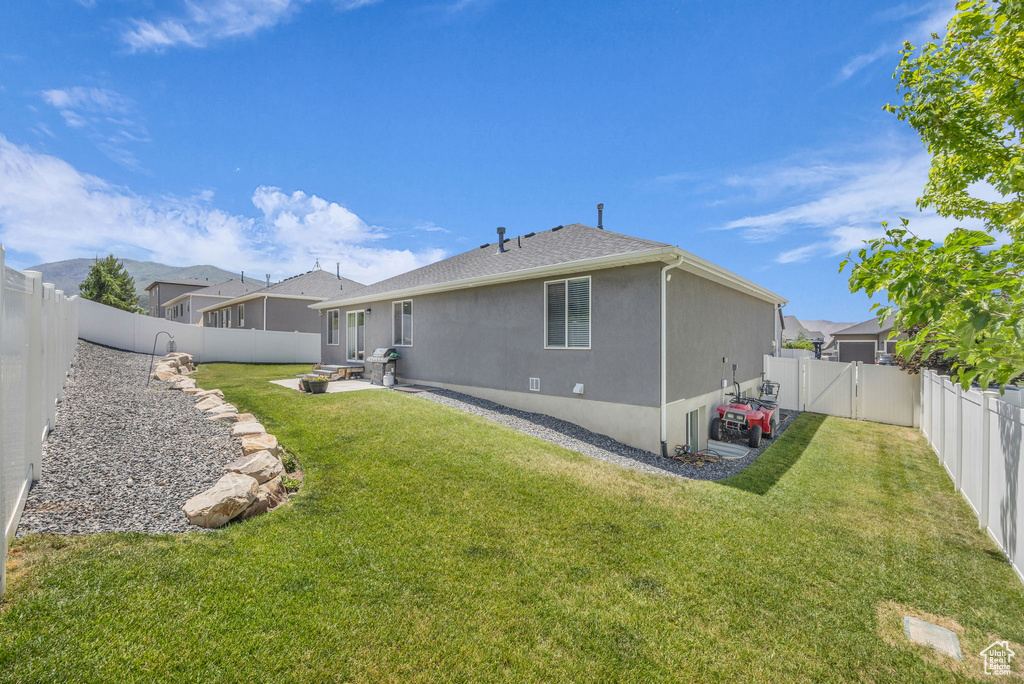 Rear view of house featuring stucco siding, a fenced backyard, a patio area, and a gate