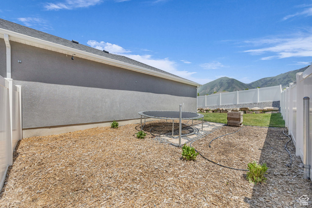 Fenced backyard featuring a trampoline and a mountain view