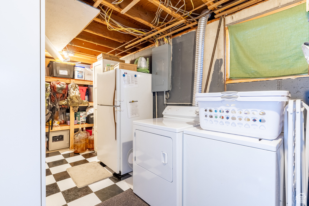 Washroom featuring washing machine and clothes dryer, electric panel, and tile patterned floors