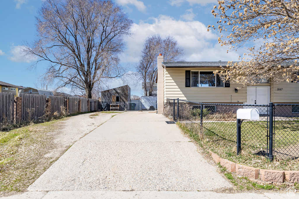 View of side of property with a chimney, a gate, and driveway