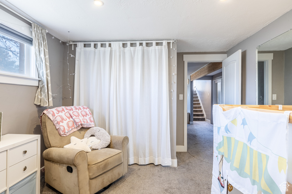 Sitting room featuring light colored carpet and stairs
