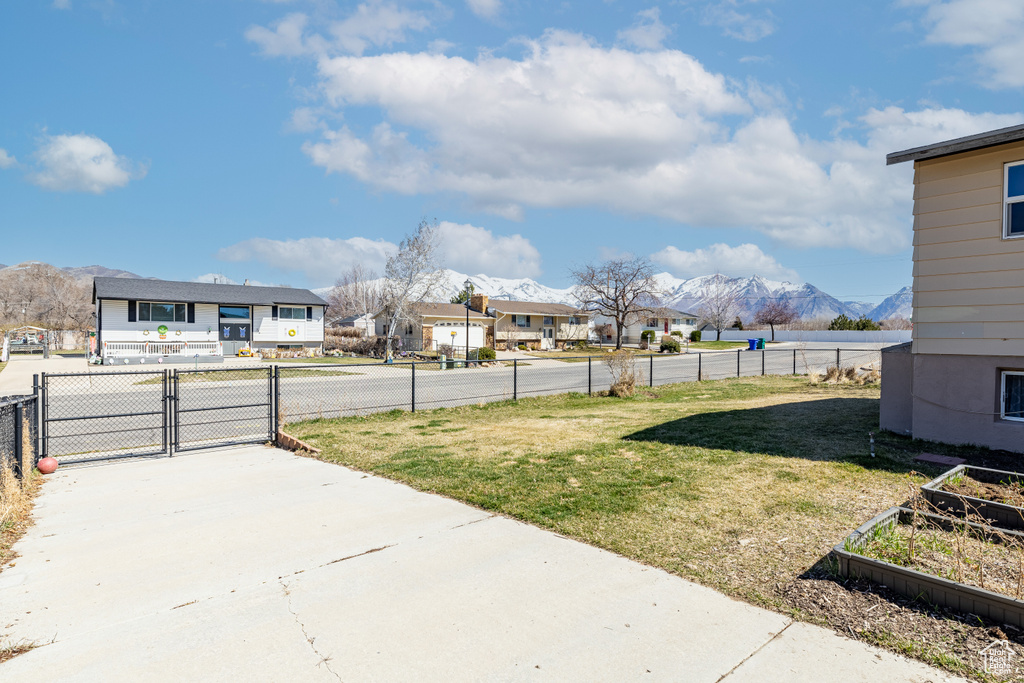 View of yard with a mountain view, a vegetable garden, a residential view, and a gate