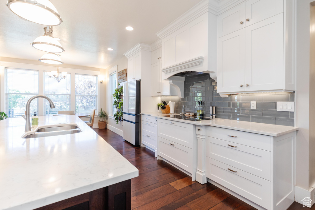 Kitchen featuring freestanding refrigerator, black electric stovetop, dark wood finished floors, white cabinetry, and tasteful backsplash