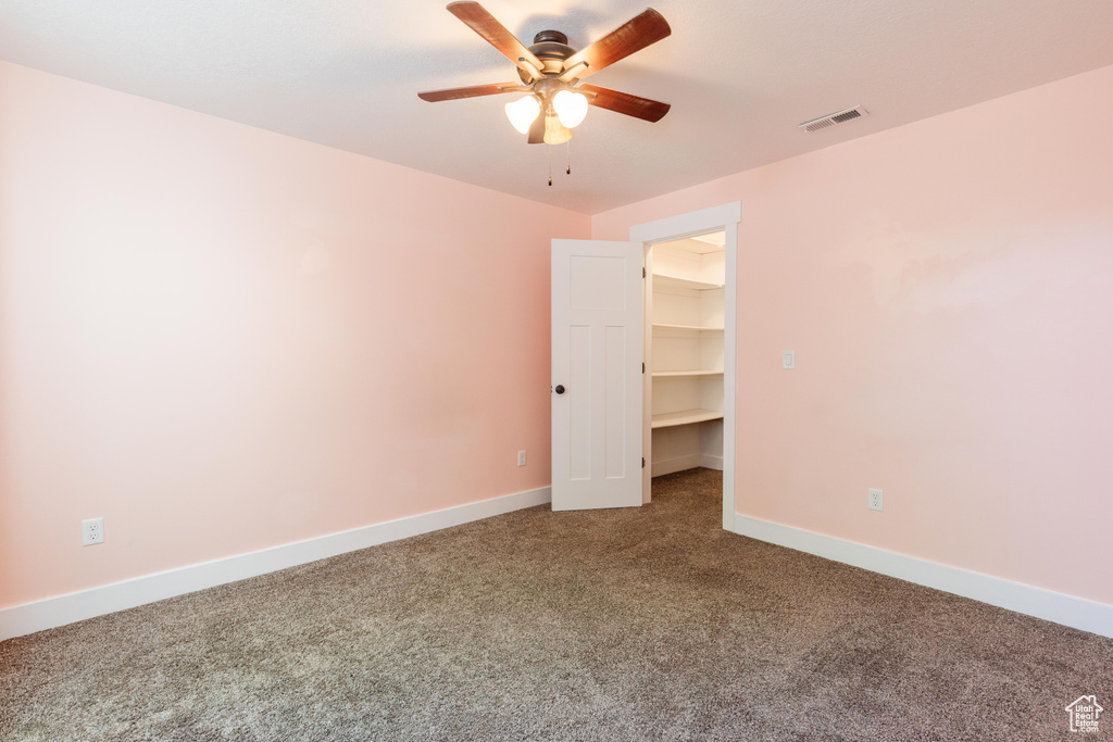 Carpeted empty room with a ceiling fan and baseboards