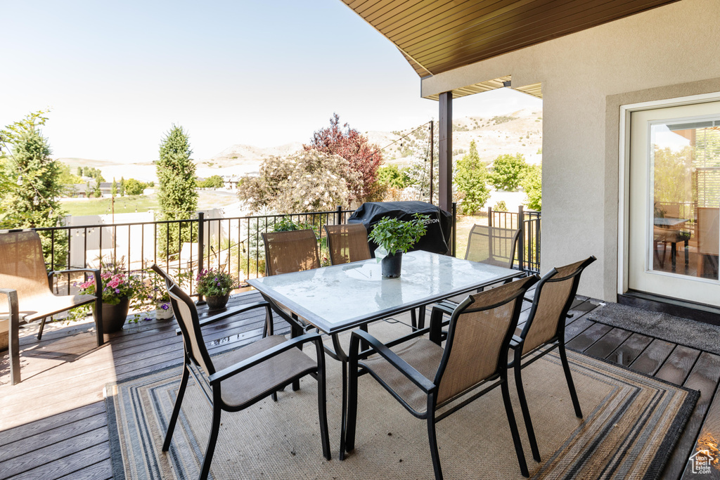 Wooden terrace with a mountain view, outdoor dining space, and a grill