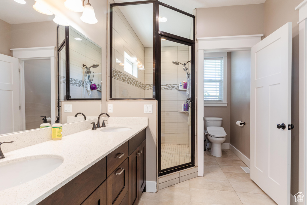Bathroom with a stall shower, tile patterned flooring, and double vanity