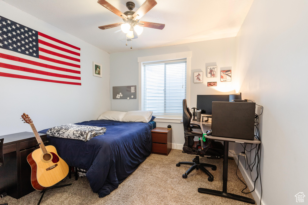 Carpeted bedroom featuring an office area and a ceiling fan