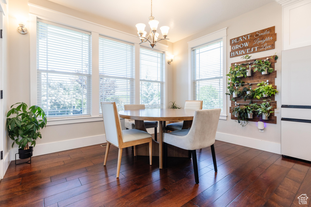 Dining space with a chandelier, healthy amount of natural light, and dark wood finished floors