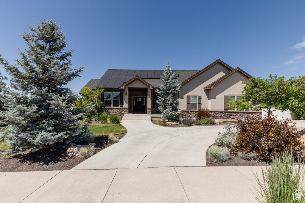 View of front of home featuring roof mounted solar panels, stone siding, and stucco siding