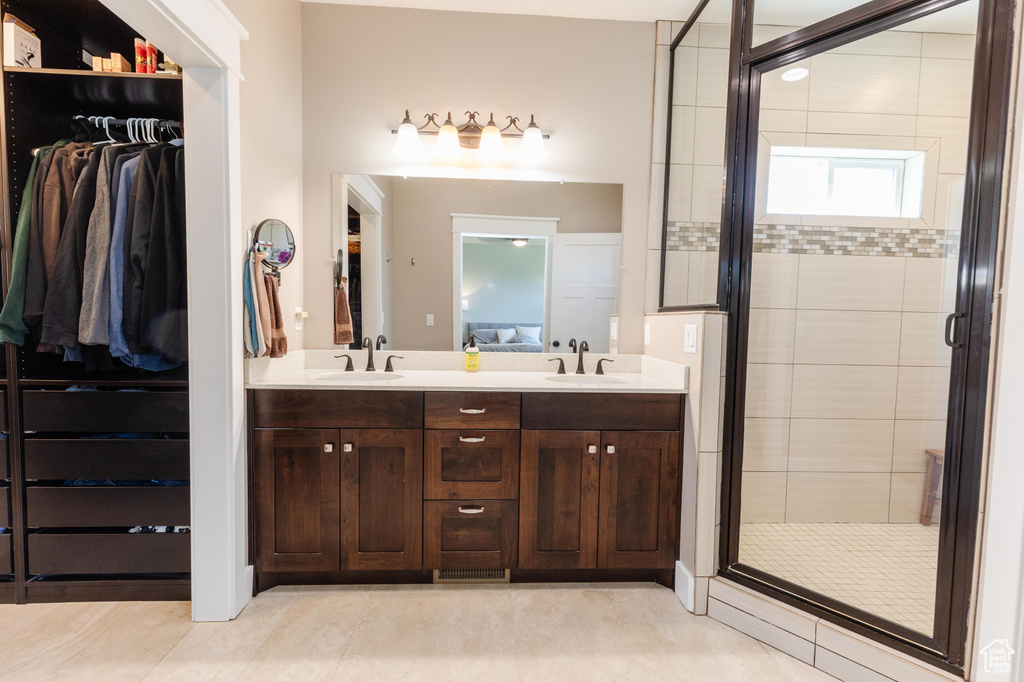 Full bathroom with a stall shower, double vanity, a spacious closet, and tile patterned flooring