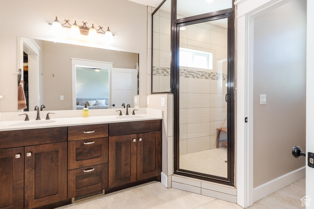 Ensuite bathroom with a stall shower, double vanity, and tile patterned floors