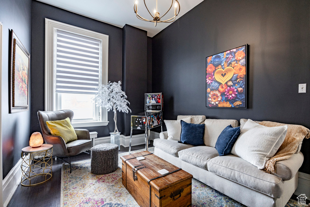 Living room with wood finished floors, a chandelier, and baseboards