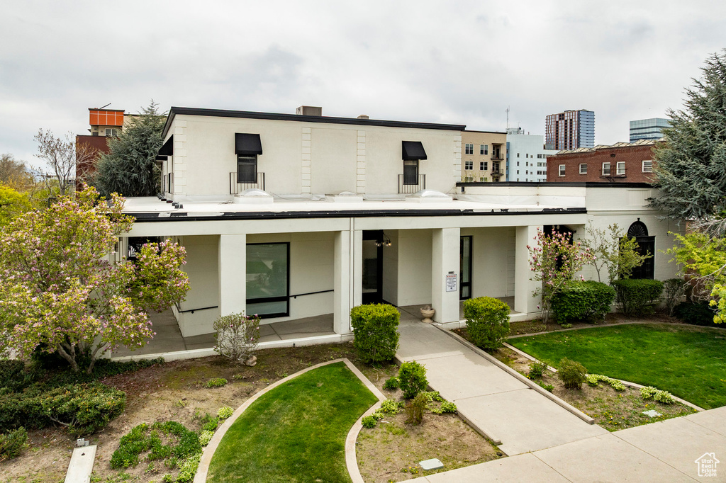 View of front of house featuring stucco siding, a porch, and a front lawn