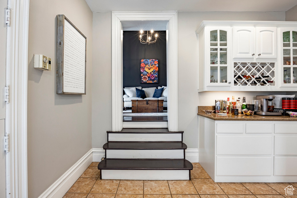 Indoor dry bar with baseboards and light tile patterned floors