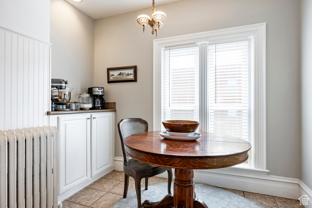 Dining area featuring radiator, light tile patterned floors, baseboards, and a chandelier
