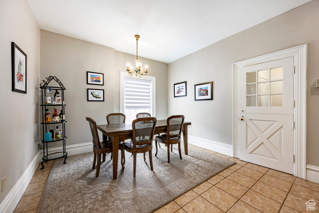 Dining area featuring a chandelier, light tile patterned flooring, and baseboards