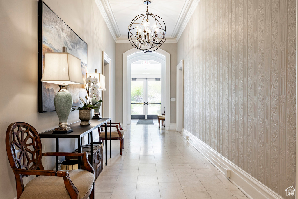 Corridor with crown molding, arched walkways, a chandelier, and baseboards