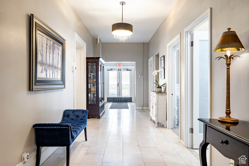 Hall with french doors, light tile patterned floors, and baseboards
